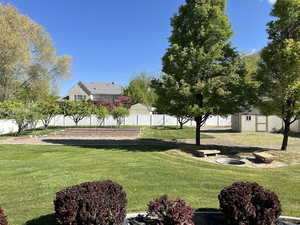 View of yard featuring fence, a storage unit, and an outdoor structure