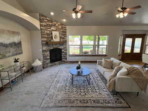 Carpeted living area with a ceiling fan, lofted ceiling, a wealth of natural light, and a fireplace