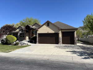 View of front of house featuring fence, stone siding, stucco siding, concrete driveway, and an attached garage