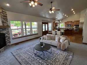 Carpeted living area with a ceiling fan, baseboards, vaulted ceiling, and visible vents