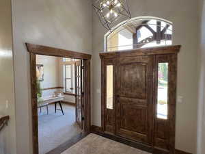 Entrance foyer with a healthy amount of sunlight, baseboards, a high ceiling, and a chandelier