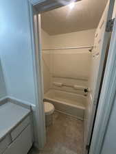 Full bathroom featuring toilet, a textured ceiling, and washtub / shower combination