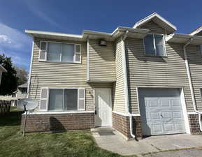 View of property with an attached garage and brick siding