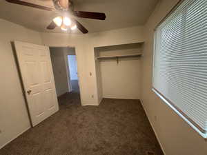 Unfurnished bedroom featuring a closet, carpet flooring, baseboards, and a ceiling fan