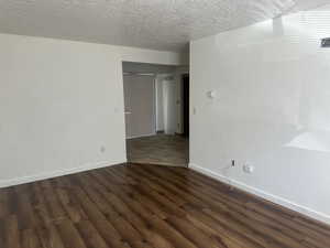 Spare room with baseboards, dark wood-style floors, a textured ceiling, and visible vents