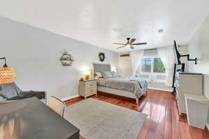 Bedroom featuring baseboards, a ceiling fan, dark wood-style flooring, and a textured ceiling