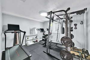 Exercise room featuring baseboards and a textured ceiling