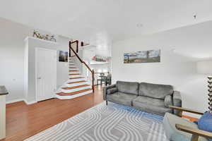 Living area with baseboards, stairs, and wood finished floors