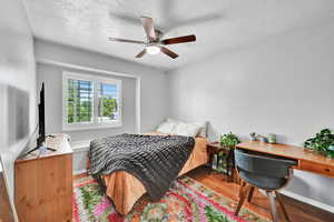 Bedroom with baseboards, a ceiling fan, a textured ceiling, and wood finished floors