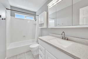 Bathroom with vanity, tile patterned floors, shower / bath combo, and toilet