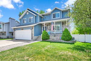 Traditional-style home with fence, an attached garage, a front lawn, covered porch, and driveway
