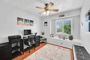 Office space featuring baseboards, a textured ceiling, ceiling fan, and wood finished floors