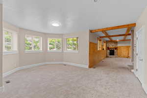 Unfurnished living room featuring wooden walls, a healthy amount of sunlight, carpet, and a fireplace