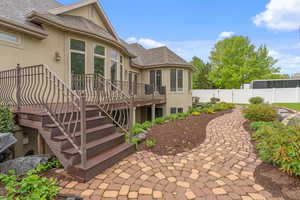 Back of property featuring a deck, fence, stairs, and stucco siding