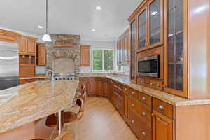 Kitchen with a sink, built in appliances, a kitchen breakfast bar, and light wood-style floors