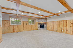 Unfurnished living room featuring wainscoting, wood walls, and beam ceiling