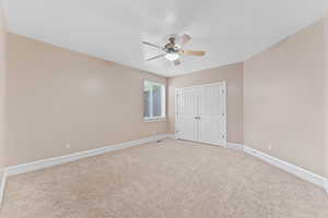 Unfurnished bedroom featuring a ceiling fan, baseboards, light carpet, and a closet