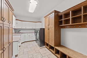 Laundry room featuring cabinet space, washing machine and dryer, a sink, and stone tile flooring