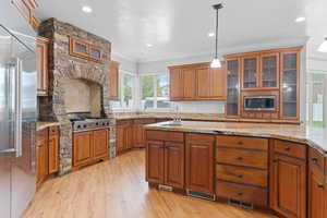 Kitchen featuring brown cabinets, appliances with stainless steel finishes, ornamental molding, and a sink