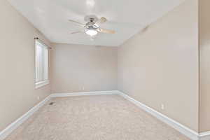 Spare room with light colored carpet, a ceiling fan, and baseboards