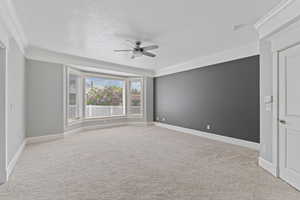 Carpeted empty room with crown molding, baseboards, and a ceiling fan