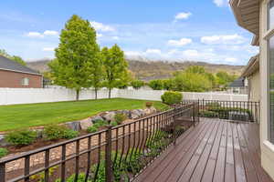 Wooden terrace featuring a lawn, a mountain view, and a fenced backyard