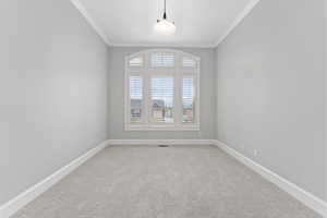 Empty room featuring crown molding, baseboards, and light colored carpet