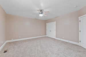 Carpeted empty room with visible vents, baseboards, and ceiling fan