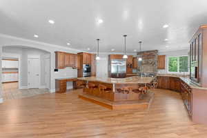 Kitchen featuring brown cabinets, stainless steel appliances, a spacious island, and light wood-type flooring