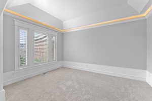 Unfurnished room featuring visible vents, carpet, and vaulted ceiling