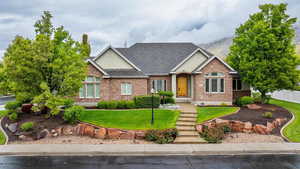 View of front of home featuring brick siding, fence, a front yard, and roof with shingles