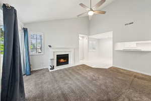 Unfurnished living room with ceiling fan, visible vents, a tiled fireplace, and a wealth of natural light