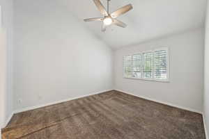 Carpeted spare room featuring baseboards, ceiling fan, and vaulted ceiling