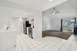 Kitchen featuring a ceiling fan, light colored carpet, stainless steel appliances, a sink, and under cabinet range hood