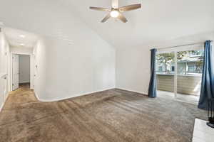 Empty room featuring ceiling fan, light colored carpet, baseboards, and lofted ceiling