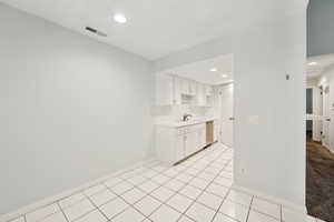 Kitchen featuring stainless steel dishwasher, visible vents, baseboards, light countertops, and a sink