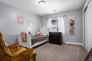 Bedroom with visible vents, baseboards, carpet floors, and a closet