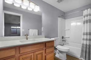 Full bath featuring visible vents, shower / bathtub combination with curtain, toilet, and vanity