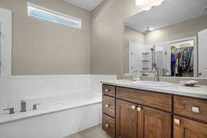 Full bathroom with vanity, a stall shower, a walk in closet, and a garden tub