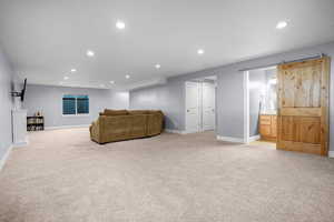 Carpeted living room with recessed lighting, a barn door, and baseboards
