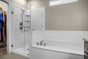 Full bath featuring a garden tub, a walk in closet, and a shower stall