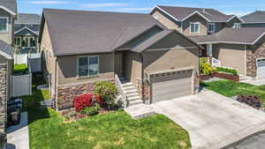 Craftsman inspired home featuring a front lawn, stucco siding, driveway, and stone siding