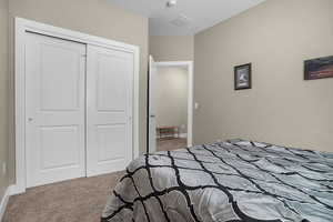 Carpeted bedroom featuring a closet and baseboards