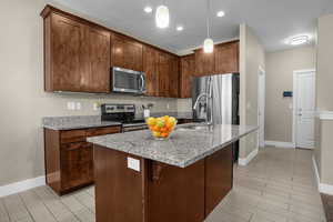 Kitchen featuring a sink, baseboards, light stone countertops, and stainless steel appliances