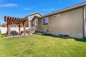 Back of house featuring fence, a pergola, stucco siding, a patio area, and a yard