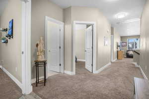 Hallway with baseboards and light colored carpet