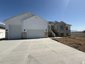 View of front of home featuring a garage, board and batten siding, driveway, and stone siding