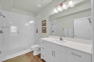 Bathroom with toilet, a shower stall, wood finished floors, and vanity