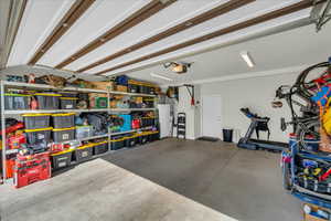 Garage featuring a garage door opener and white refrigerator