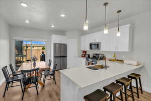 Kitchen with a sink, light wood finished floors, stainless steel appliances, baseboards, and a peninsula